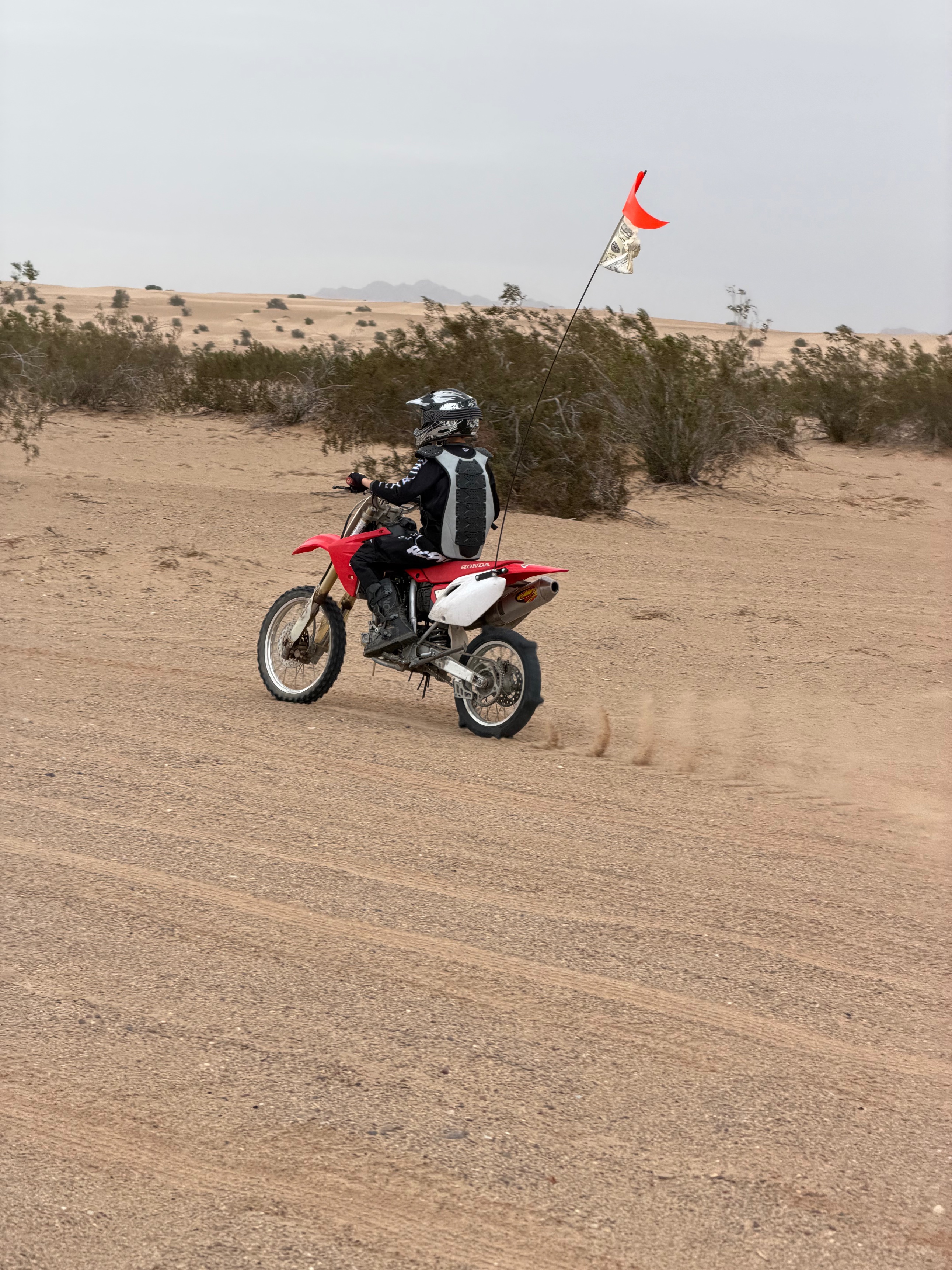 Lucas riding a red Honda dirt bike in the Glamis sand dunes